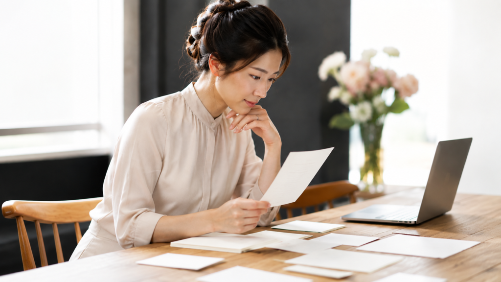 結婚式のペーパーアイテムをパソコンと見比べて確認する新婦様